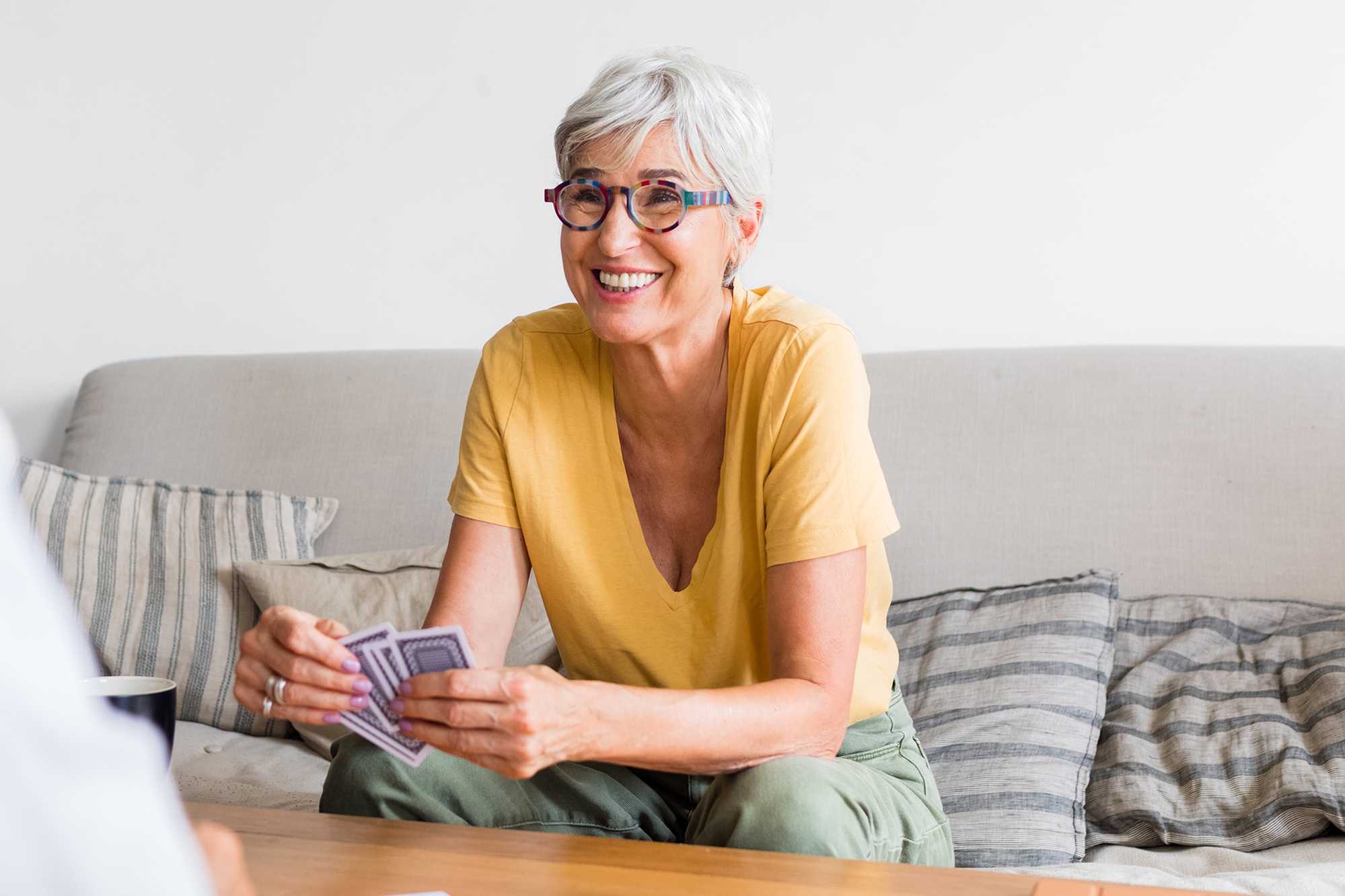 Older woman playing cards while sitting on couch Older woman playing cards while sitting on couch