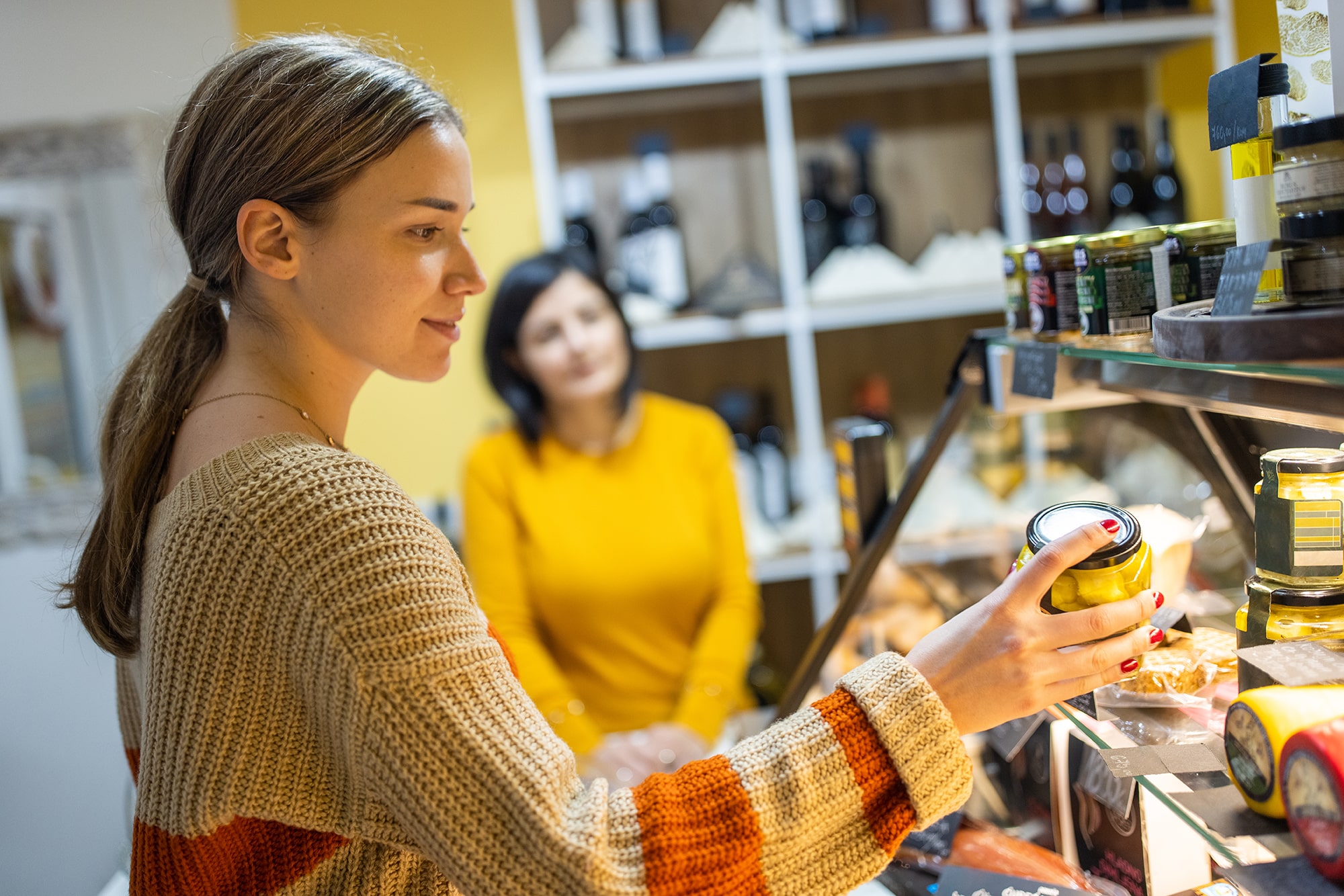 Woman is looking at item in grocery cheese case Woman is looking at item in grocery cheese case
