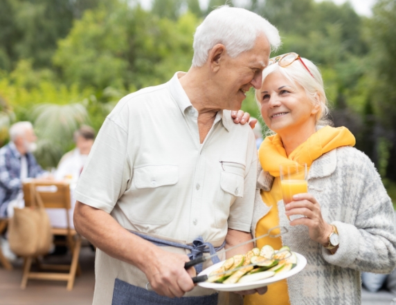 Older couple barbequing outside