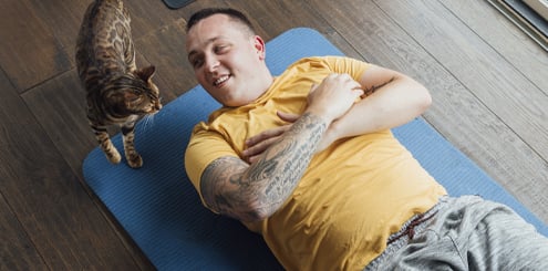 Man doing yoga with his cat