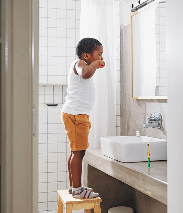 Young boy brushing his teeth in front of the mirror
