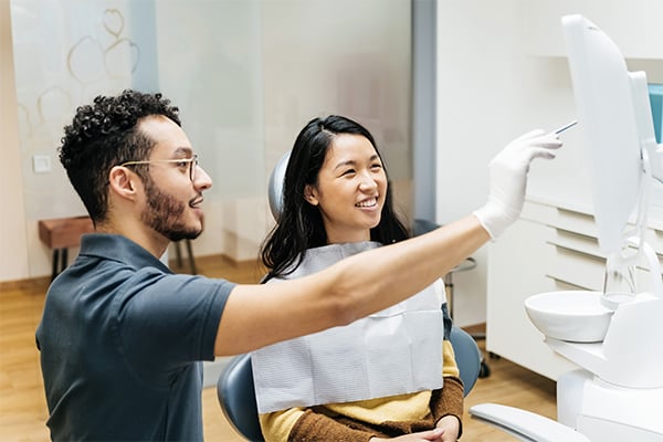 Male dentist showing female patient something on a monitor