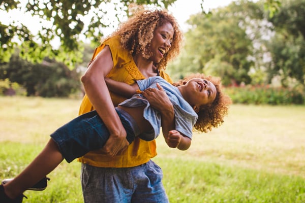 Young mom and daughter playing in grass