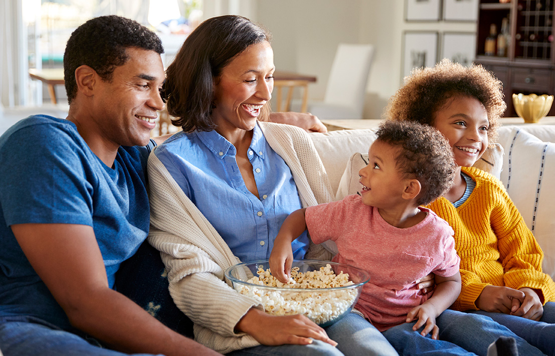 Family sitting on couch, eating popcorn Family sitting on couch, eating popcorn