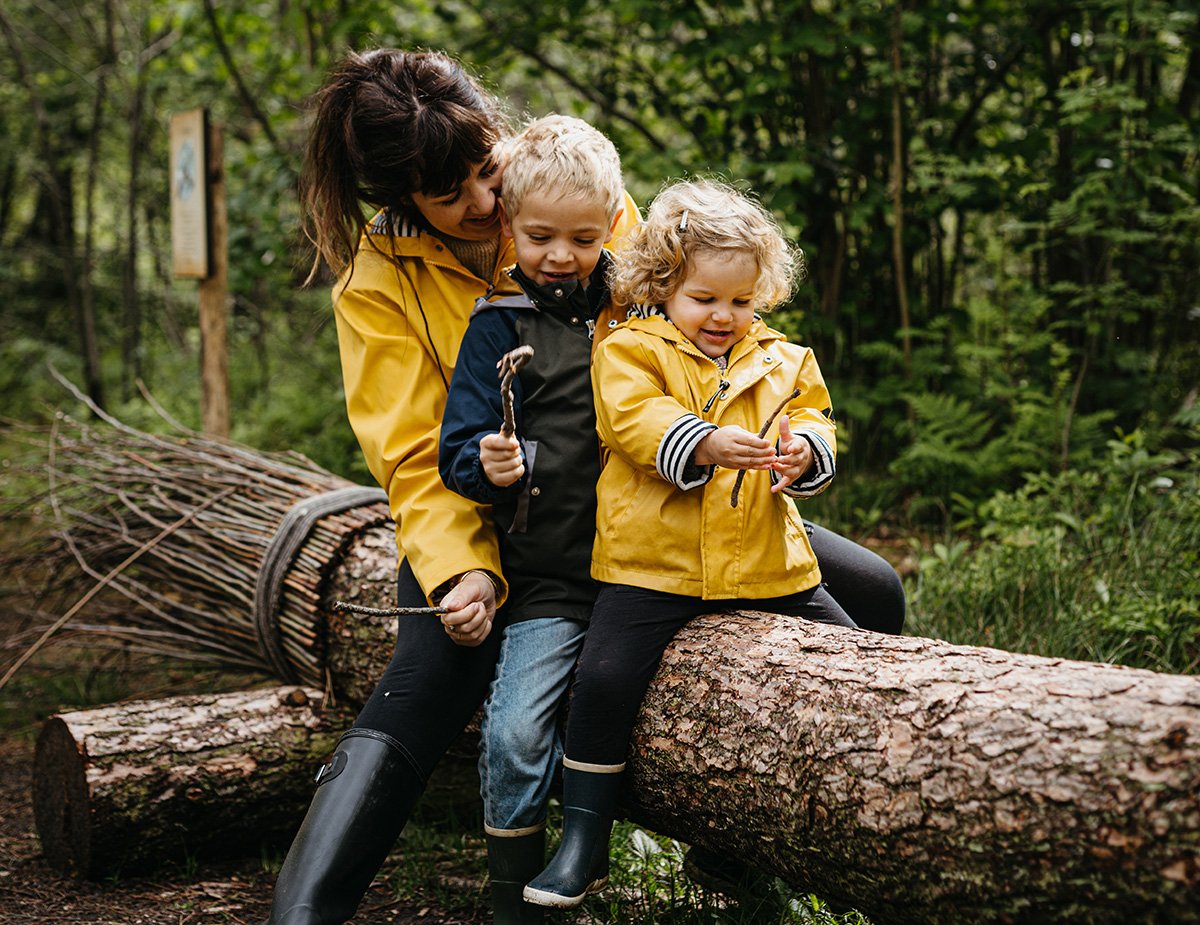 Woman sitting on log with two children